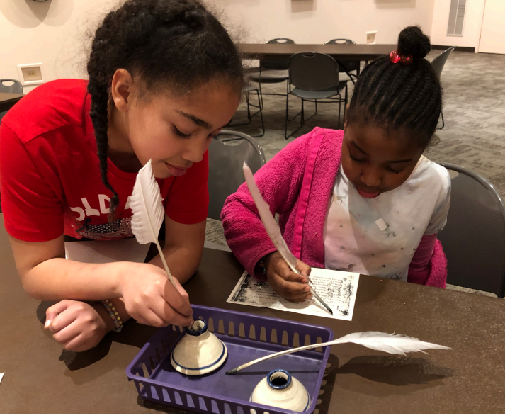 Students writing with feathers