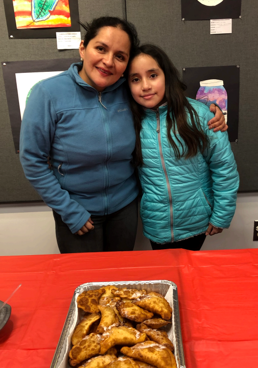 parent and child standing in front of dish of food